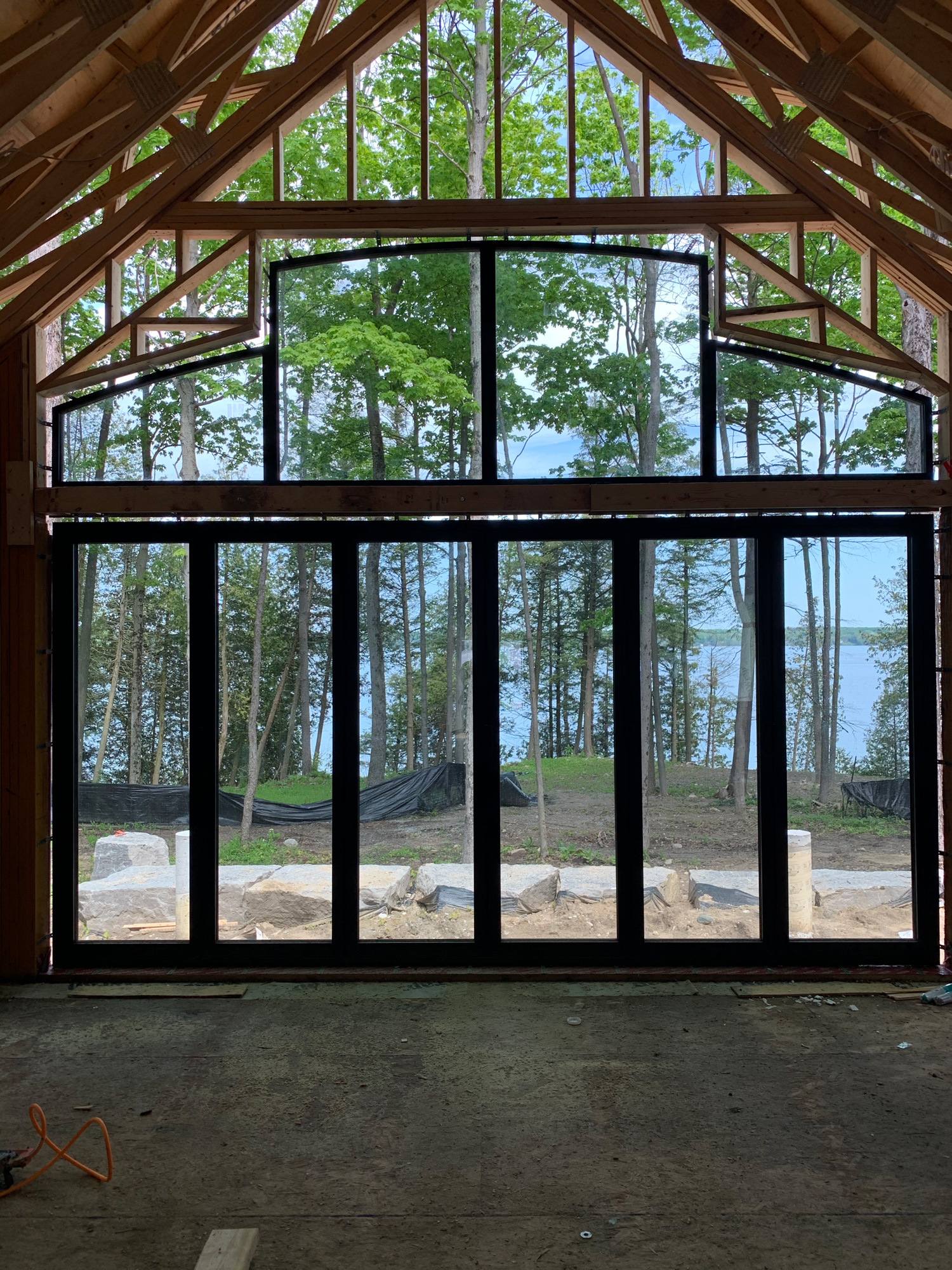 Lake Simcoe cottage installation featuring Reynaers Aluminum CF77 folding doors with SL38 European cambered top windows above, framing waterfront views.