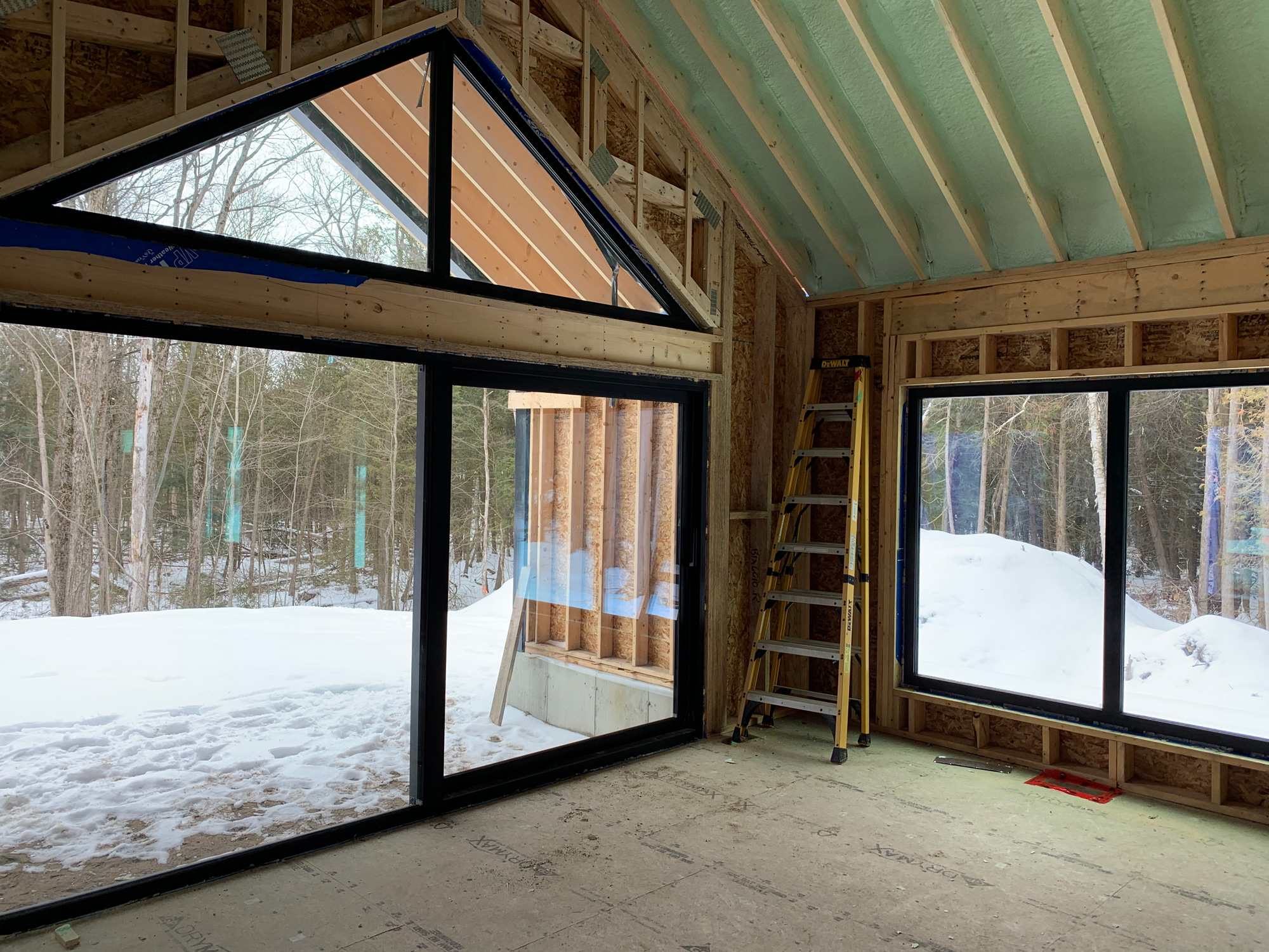 Interior of a master bedroom in a Barrie luxury home with Reynaers CS77HI windows and a CP130LS lift sliding door opening to the snowy landscape.