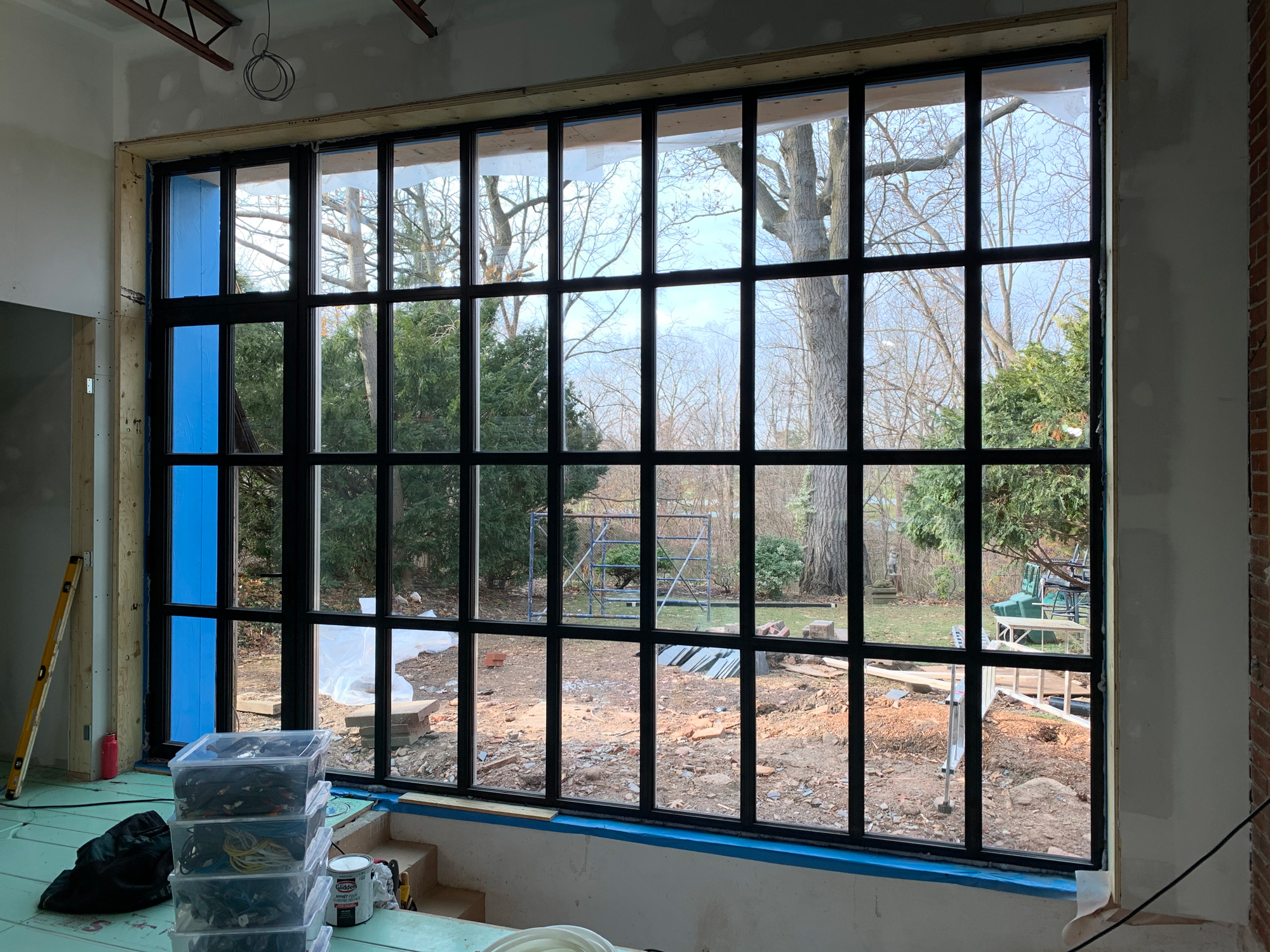 Installation of a Reynaers Aluminum SL38 true divided feature window with integrated side-hung door, creating a striking backyard focal point in Oakville.