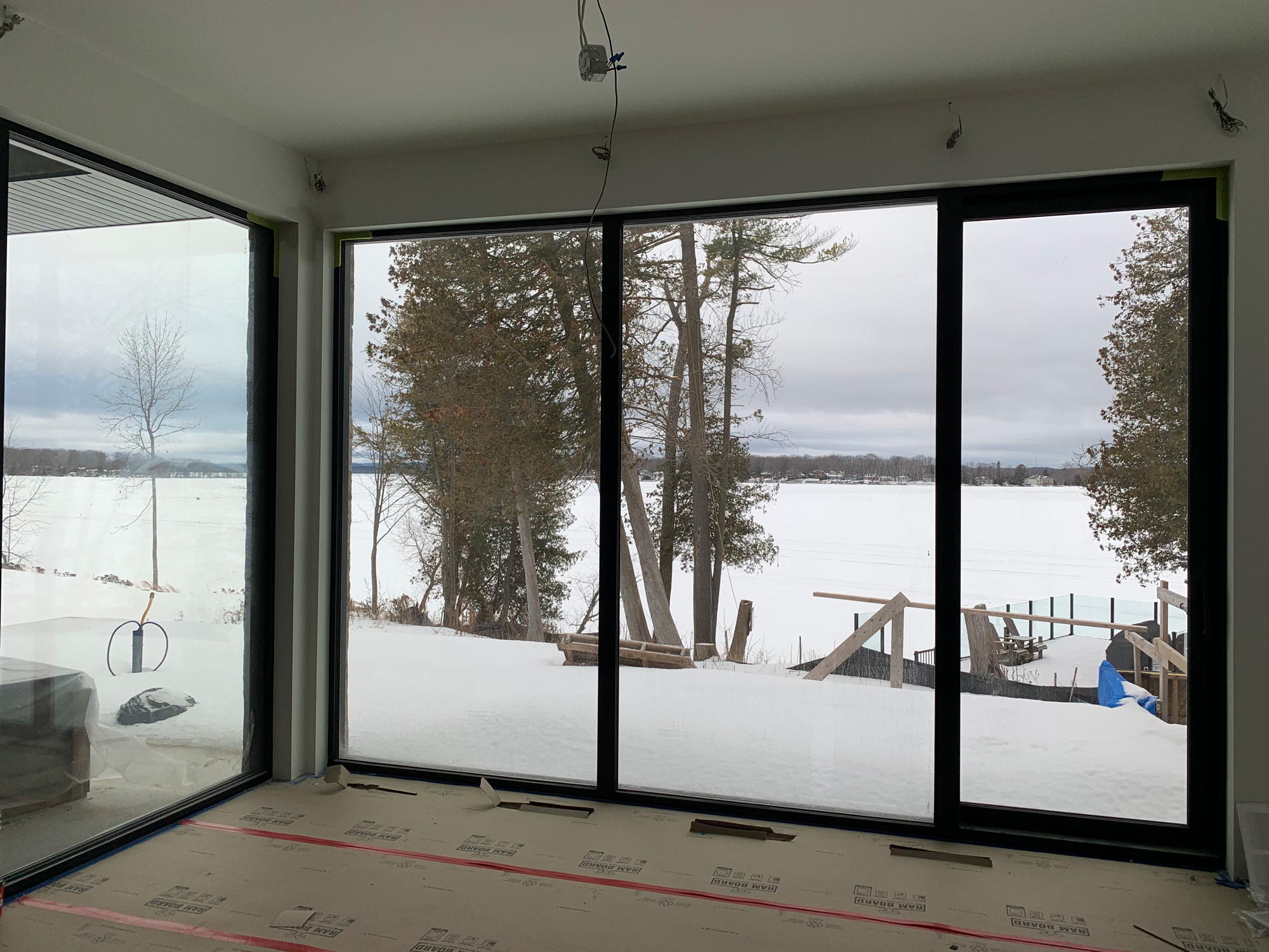Interior view of a Muskoka lakeside home with Reynaers Aluminum SL38 windows combining fixed glazing and full-height tilt-turn units overlooking the snowy waterfront.