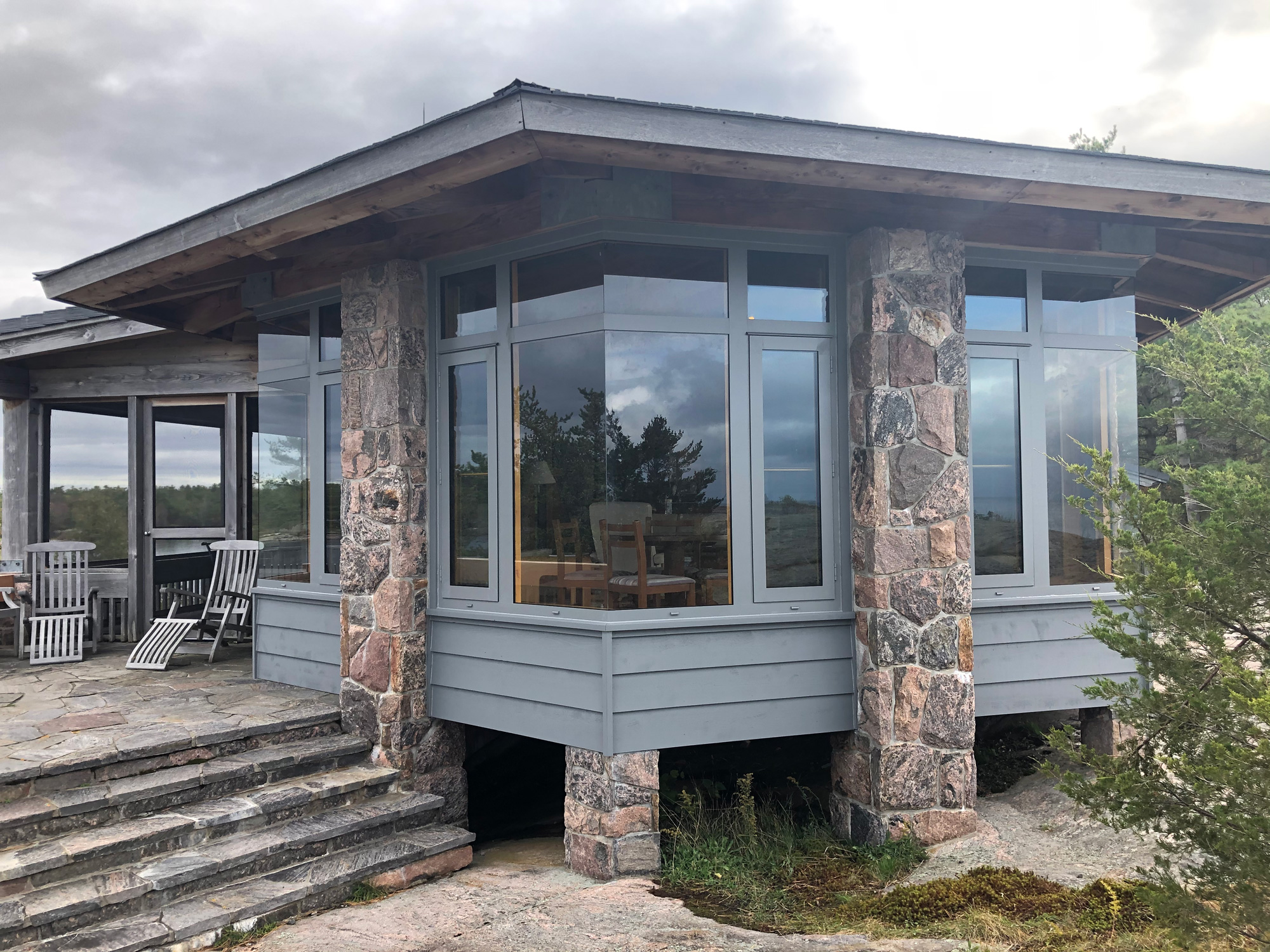 Exterior view of completed facade with Reynaers CS77 dual-colour windows, combining fixed glazing and casement units on a Georgian Bay island cottage.
