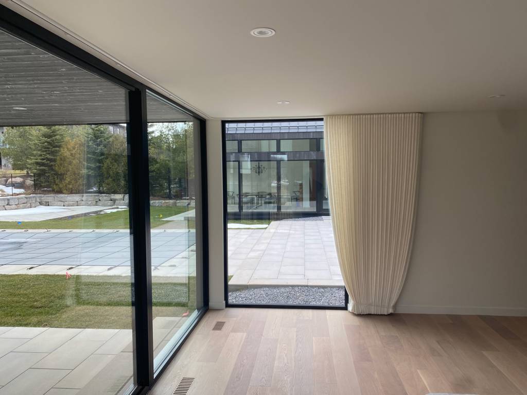 Reynaers Slim-Patio sliding door with SL38 fixed glazing overlooking a courtyard, with SL38 transoms and MasterLine 8 patio doors visible.