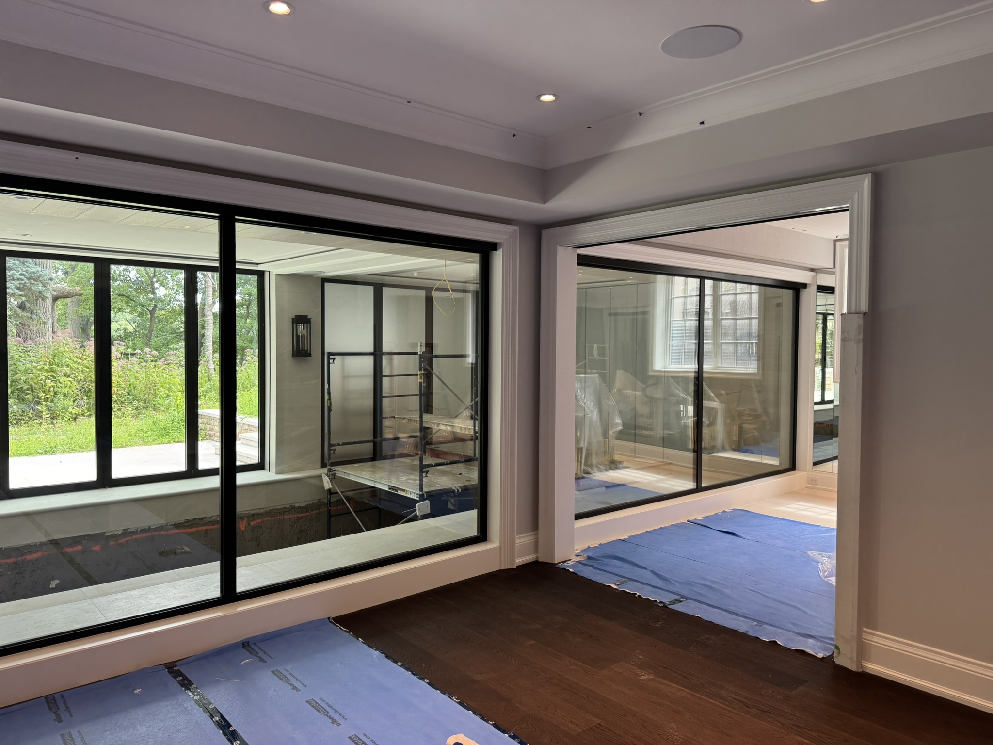Interior view of a Toronto modern home showing two Reynaers Aluminum MasterLine 8 window walls dividing the swimming pool area from the living spaces, maximizing light and transparency.