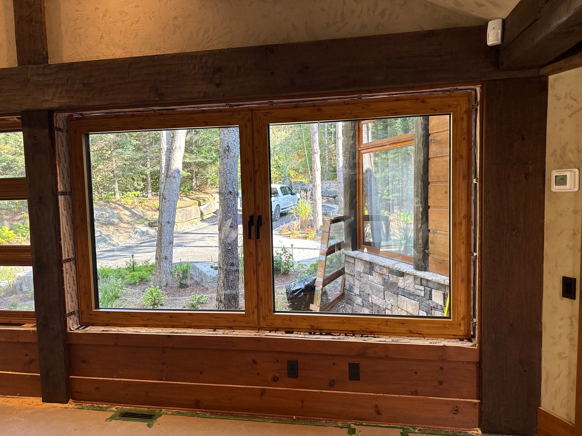Interior view of a Mont Tremblant cottage after wood sublimation applied to Reynaers Aluminum windows, seamlessly matching the rustic timber design.