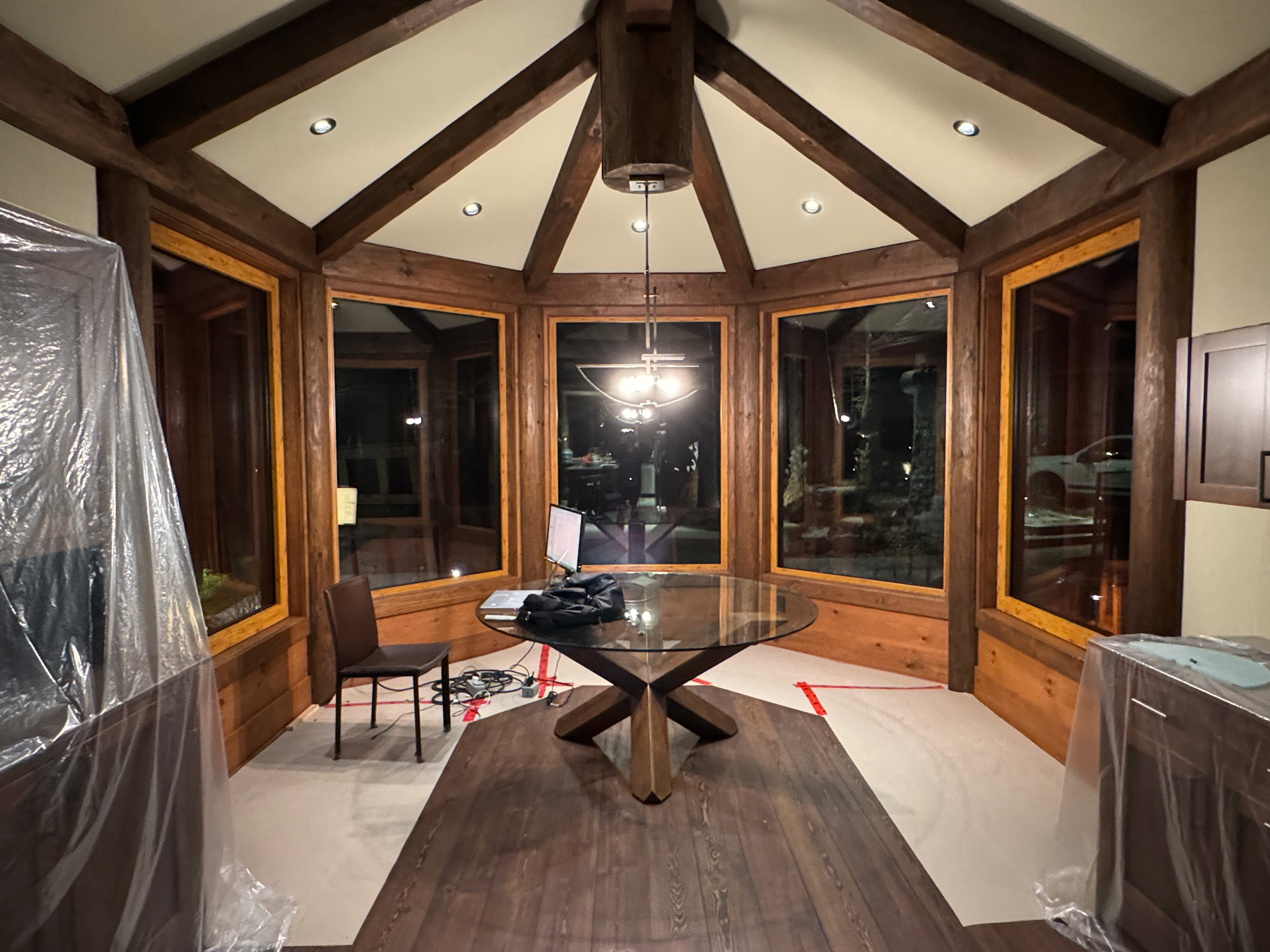 Dining room of a cottage featuring Reynaers Aluminum MasterLine 8 windows with three fixed units and two tilt-turn operators framed in timber beams.
