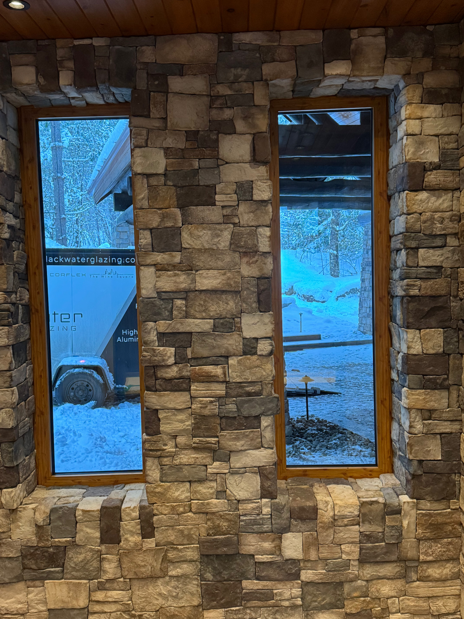 Interior view of a cottage wall with two Reynaers Aluminum MasterLine 8 fixed windows framed in natural stone, combining modern performance with rustic design.
