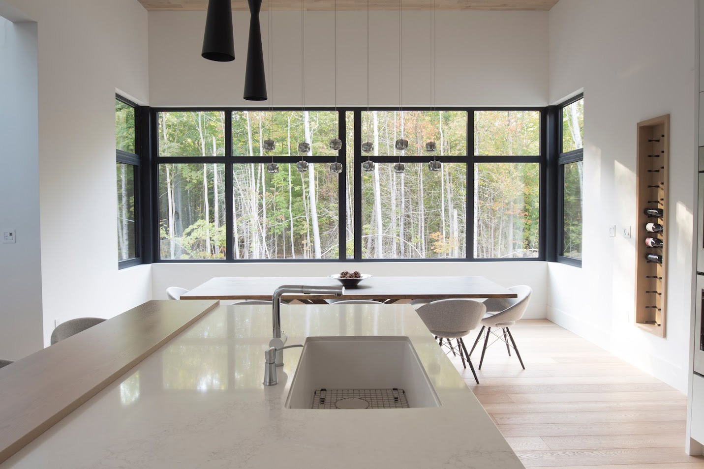 Dining room of a Barrie modern home featuring Reynaers Aluminum CS77 windows with fixed glazing and operable vents, creating a modern grid design overlooking the forest.