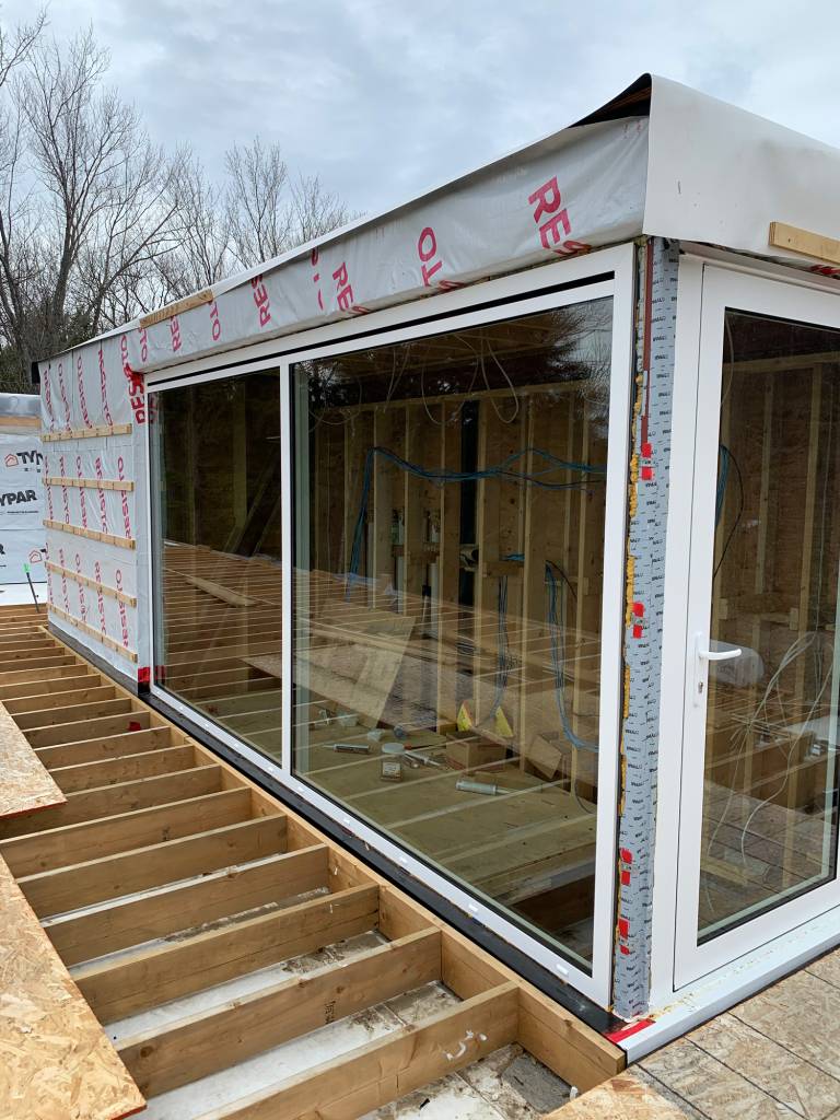 Installation of Reynaers Aluminum CS77 window and door system enclosing a covered stairwell at a Lake Rosseau cottage, providing durability and modern performance.