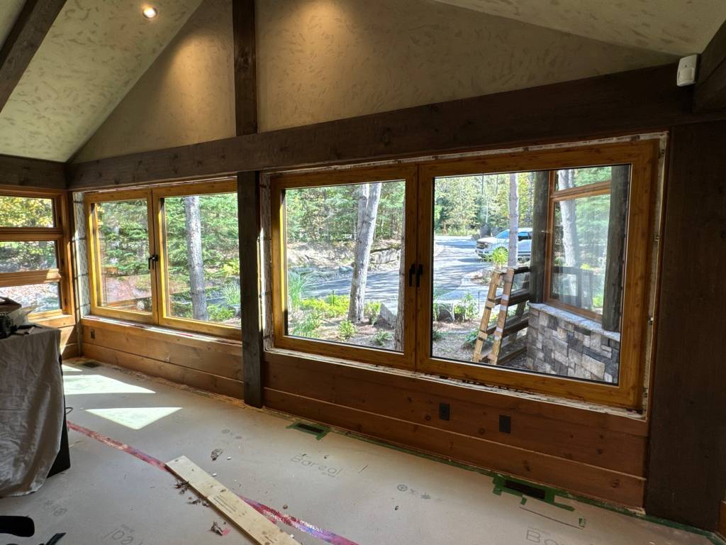 Wider interior view of a Mont Tremblant cottage wall showcasing multiple Reynaers Aluminum windows finished with wood sublimation for a natural timber appearance.