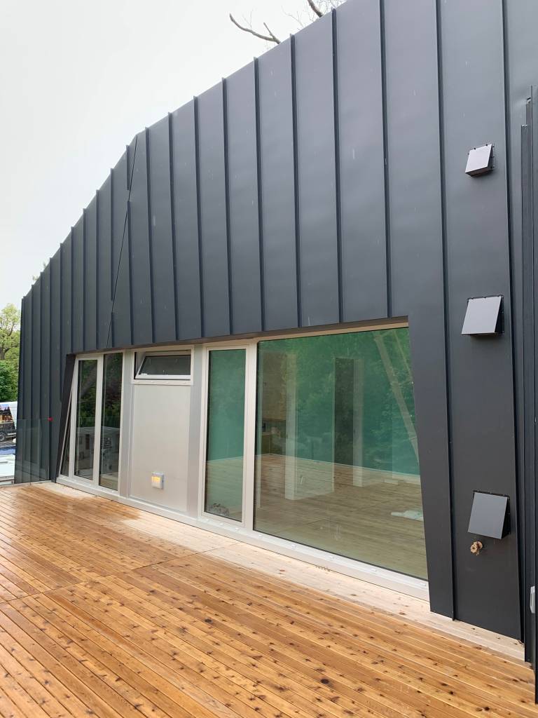 Combination of fixed Reynaers CS77 glazing, tilt-and-turn windows, and panel insert in natural anodized finish on a modern Sarnia home.