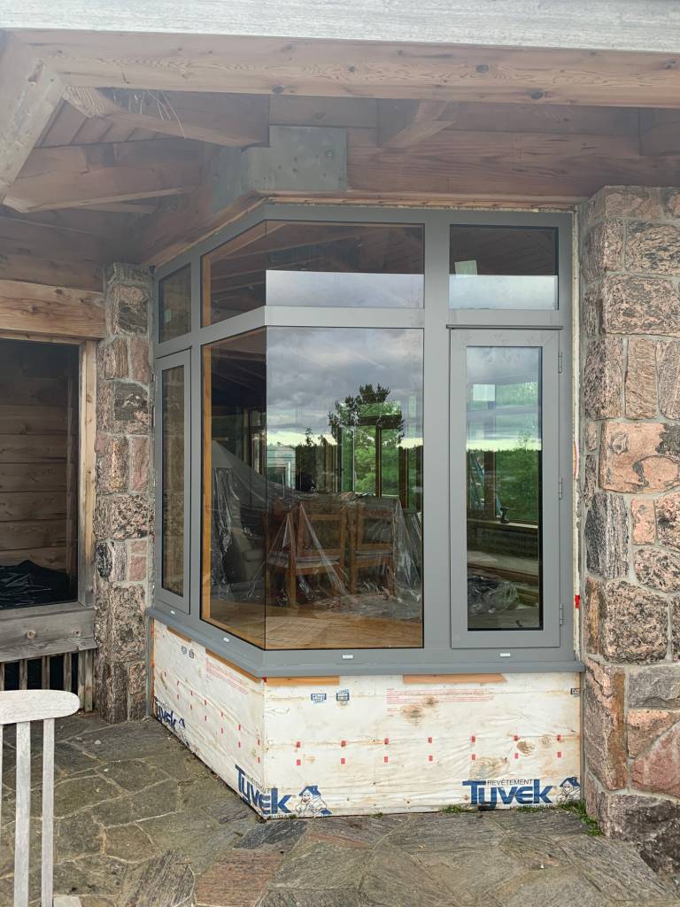 Reynaers CS77 dual-colour open corner windows with grey exterior and wood sublimation interior on a Georgian Bay island cottage built for extreme weather.