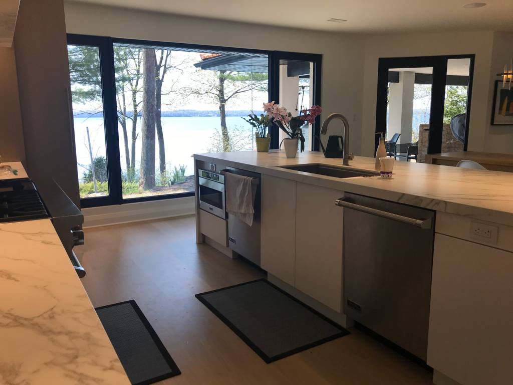 Kitchen view of a Lake Simcoe modern home featuring Reynaers MasterLine 8 fixed glazing, tilt-turn windows, and a side-hung door with sidelite.