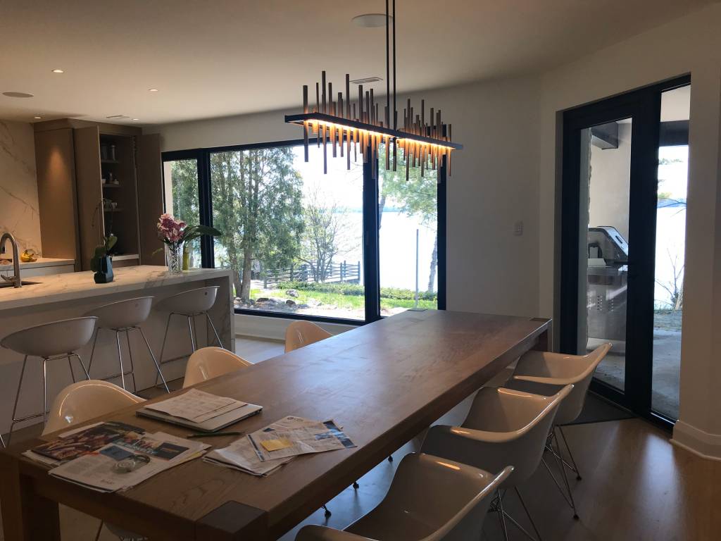 Dining area of a Lake Simcoe modern home with Reynaers MasterLine 8 fixed glazing, tilt-turn windows, and a side-hung door with sidelite.