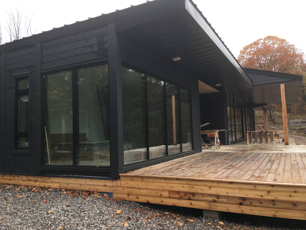 Exterior view of a Muskoka cottage featuring Reynaers Aluminum SL38 windows with slim profiles, combining fixed and operable glazing in a modern black facade.