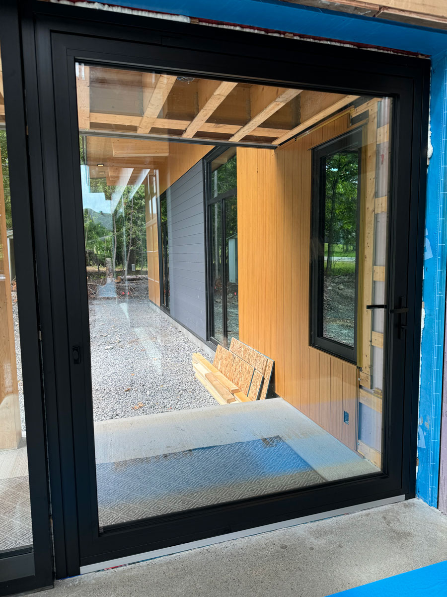 Interior view of a 6' x 8' Reynaers MasterLine 8 black pivot entry door in a home along the Ottawa River near Ottawa.