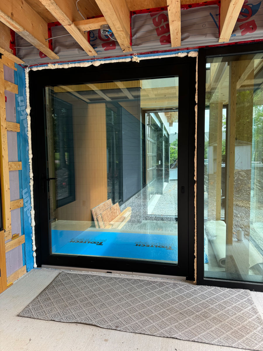 Exterior view of a 6' x 8' Reynaers MasterLine 8 black pivot entry door on a home along the Ottawa River near Ottawa.