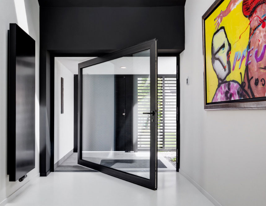 Reynaers glamour photo of an 8' x 8' MasterLine 8 black pivot door, partially open in a modern European home.