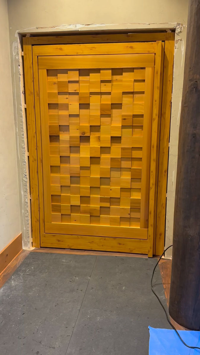 Closed Reynaers MasterLine 8 interior pivot door with geometric wood panel insert in a Mont-Tremblant cottage.