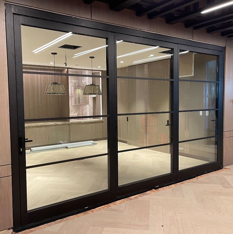 Closed Reynaers MasterLine 8 black Landscape Pivot doors with horizontal muntins, forming a sleek interior partition in a downtown Toronto hotel.