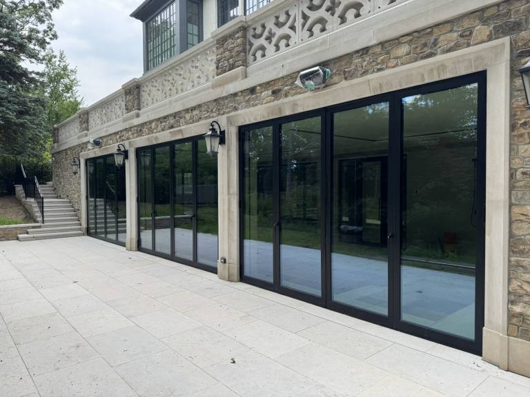 Exterior view of three Reynaers CF77 black folding doors enclosing the indoor swimming pool of a luxury residence in Toronto, ON.