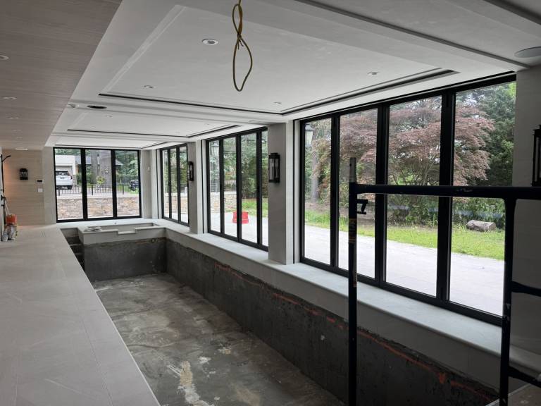 Interior view of four Reynaers CF77 folding doors, including three- and four-panel black units, enclosing a swimming pool in a Toronto luxury residence.