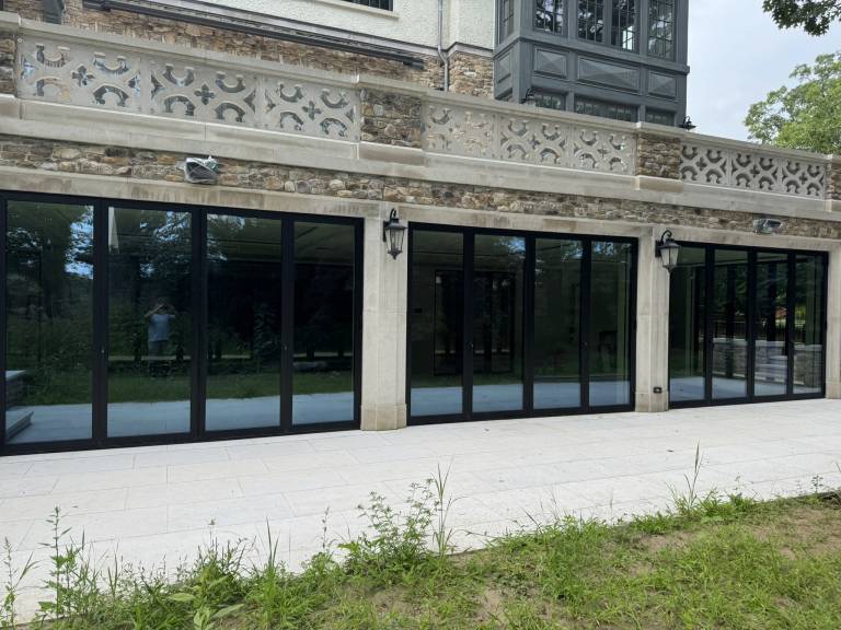 Alternate exterior view of three Reynaers CF77 black folding doors enclosing the indoor swimming pool of a luxury residence in Toronto, ON.