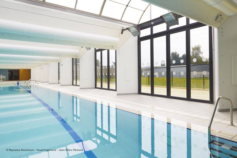 Reynaers CF77 folding doors with zero threshold opening to an indoor swimming pool, glamour photo.