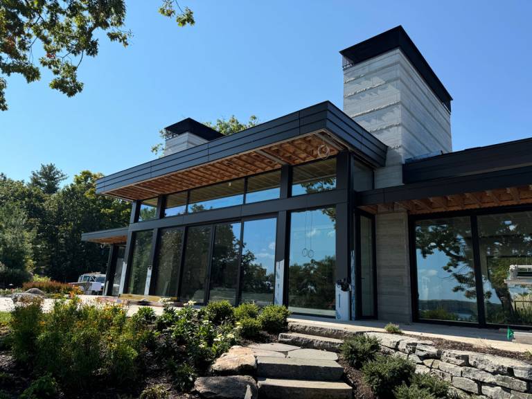 Exterior angle of a Thousand Islands residence showcasing Reynaers CP155 lift-slide doors alongside CS77 fixed windows.