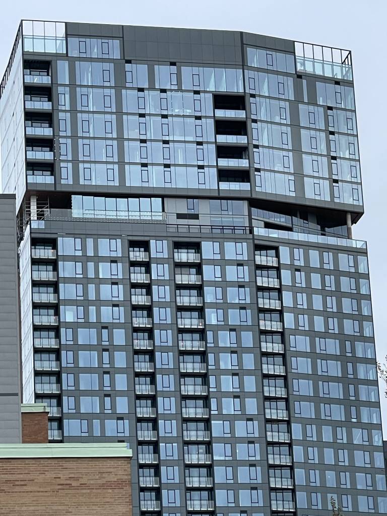 Exterior view of a Montreal high-rise showing the closed Reynaers HiFinity pool enclosure between the 31st and 32nd floors.